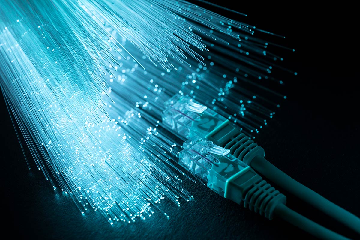 På bildet er det avbildet en nærbildevisning av blå optiske fibre med ethernet-kabler, noe som illustrerer moderne bredbåndsteknologi.
