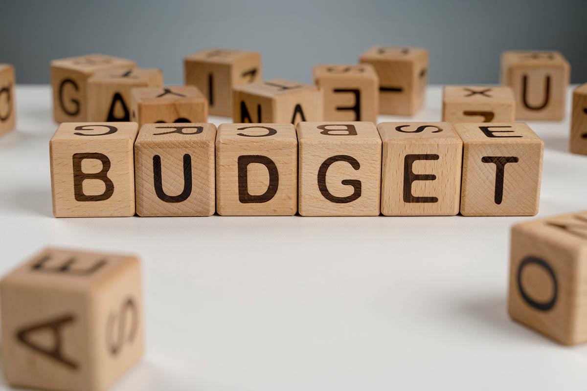 På bildet er det vist treblokker som danner ordet BUDGET, noe som symboliserer viktigheten av å planlegge et flytte hjemmefra-budsjett.